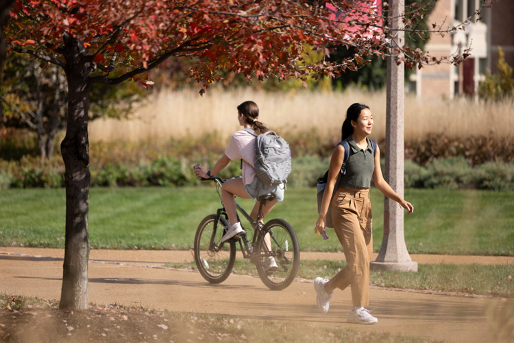 students walking and riding bike on campus